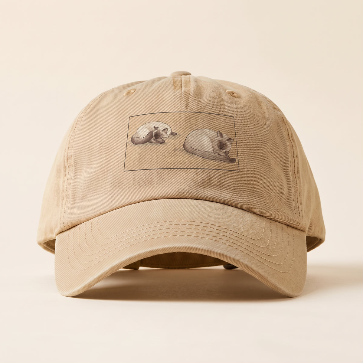Two Siamese cats asleep side by side in watercolor, printed in a framed panel on the front of a Sandstone washed cap (mockup)