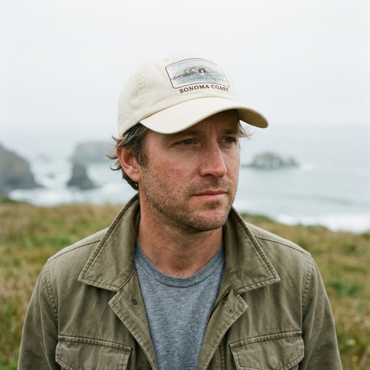 Man wearing the ivory Arched Rock washed cap on a foggy Sonoma Coast bluff